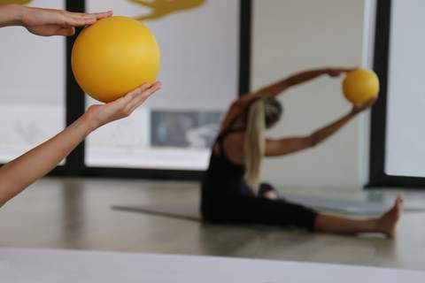 Allungamento seduto con una palla morbida durante la lezione di Pilates